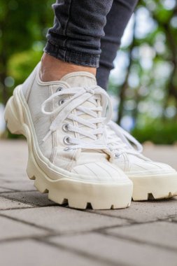 Siyah kotlu kadın bacaklarında çivili tabanlı beyaz spor ayakkabılar.