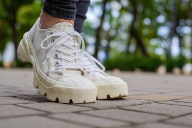 Siyah kotlu kadın bacaklarında çivili tabanlı beyaz spor ayakkabılar.