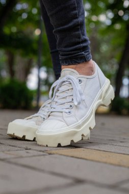 Siyah kotlu kadın bacaklarında çivili tabanlı beyaz spor ayakkabılar.