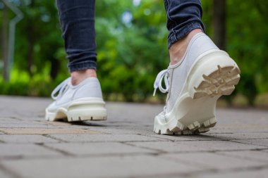 Siyah kotlu kadın bacaklarında çivili tabanlı beyaz spor ayakkabılar.