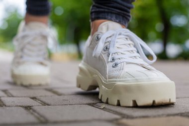 Siyah kotlu kadın bacaklarında çivili tabanlı beyaz spor ayakkabılar.