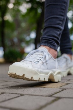 Siyah kotlu kadın bacaklarında çivili tabanlı beyaz spor ayakkabılar.