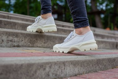 Siyah kotlu kadın bacaklarında çivili tabanlı beyaz spor ayakkabılar.