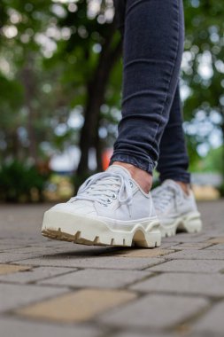 Siyah kotlu kadın bacaklarında çivili tabanlı beyaz spor ayakkabılar.
