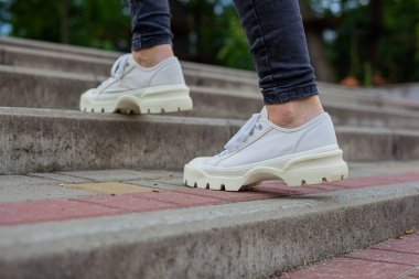 Siyah kotlu kadın bacaklarında çivili tabanlı beyaz spor ayakkabılar.