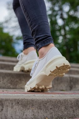 Siyah kotlu kadın bacaklarında çivili tabanlı beyaz spor ayakkabılar.