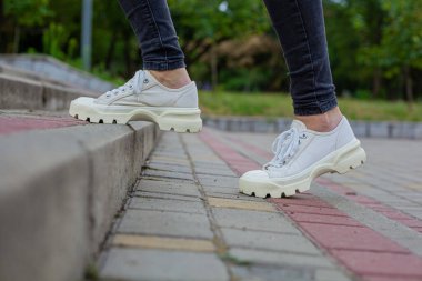 Siyah kotlu kadın bacaklarında çivili tabanlı beyaz spor ayakkabılar.