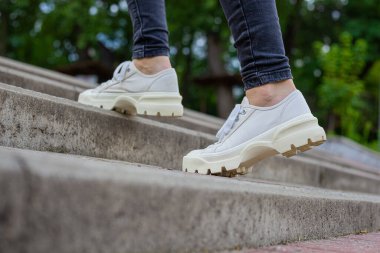 Siyah kotlu kadın bacaklarında çivili tabanlı beyaz spor ayakkabılar.