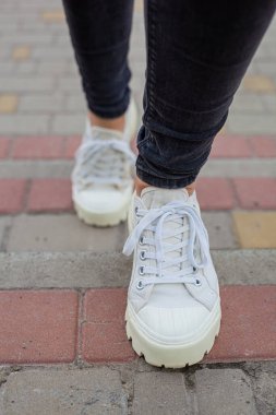 Siyah kotlu kadın bacaklarında çivili tabanlı beyaz spor ayakkabılar.
