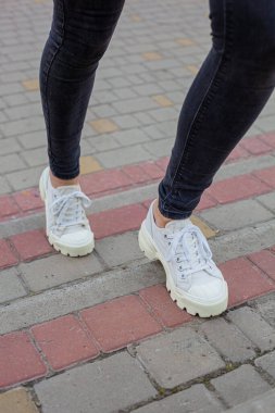 Siyah kotlu kadın bacaklarında çivili tabanlı beyaz spor ayakkabılar.