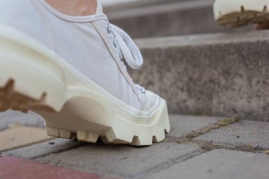 Siyah kotlu kadın bacaklarında çivili tabanlı beyaz spor ayakkabılar.