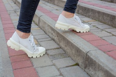 Siyah kotlu kadın bacaklarında çivili tabanlı beyaz spor ayakkabılar.