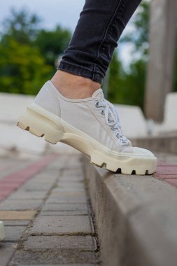 Siyah kotlu kadın bacaklarında çivili tabanlı beyaz spor ayakkabılar.