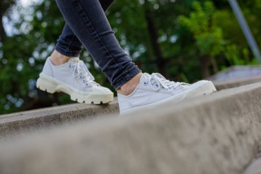 Siyah kotlu kadın bacaklarında çivili tabanlı beyaz spor ayakkabılar.