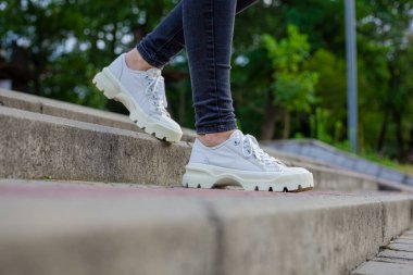 Siyah kotlu kadın bacaklarında çivili tabanlı beyaz spor ayakkabılar.