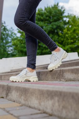 Siyah kotlu kadın bacaklarında çivili tabanlı beyaz spor ayakkabılar.
