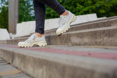 Siyah kotlu kadın bacaklarında çivili tabanlı beyaz spor ayakkabılar.