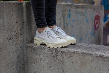 Siyah kotlu kadın bacaklarında çivili tabanlı beyaz spor ayakkabılar.