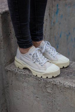 Siyah kotlu kadın bacaklarında çivili tabanlı beyaz spor ayakkabılar.