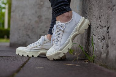 Siyah kotlu kadın bacaklarında çivili tabanlı beyaz spor ayakkabılar.