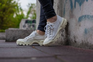 Siyah kotlu kadın bacaklarında çivili tabanlı beyaz spor ayakkabılar.