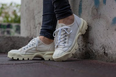 Siyah kotlu kadın bacaklarında çivili tabanlı beyaz spor ayakkabılar.