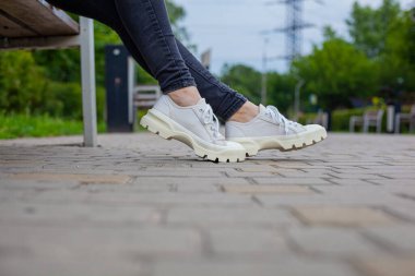 Siyah kotlu kadın bacaklarında çivili tabanlı beyaz spor ayakkabılar.