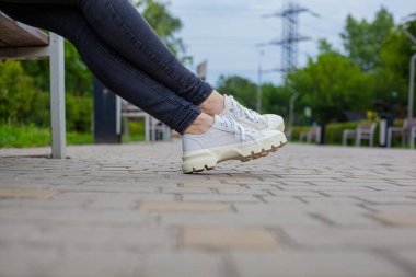 Siyah kotlu kadın bacaklarında çivili tabanlı beyaz spor ayakkabılar.