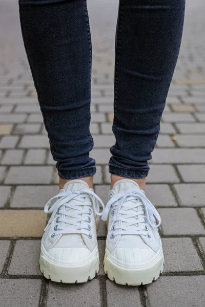 Siyah kotlu kadın bacaklarında çivili tabanlı beyaz spor ayakkabılar.