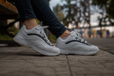 Sokakta siyah kotlu bir kızın ayağında beyaz ayakkabılar.