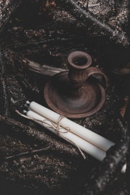 Tahta bir şamdanın yanında sicimle bağlanmış üç beyaz mum.