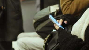 Metroda oturan akıllı telefonu kullanan bir kadın. Yeraltı treni. Cep telefonu kadınların elinde, çevrimiçi bağımlılık konsepti, SMS, sosyal medya ve bir seyahatte iletişim.
