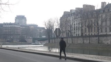 Paris 'teki Seine Nehri boyunca yürüyen bir adam, Fransa' nın başkenti..