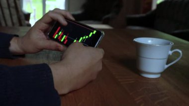 Adam evdeki cep telefonundan borsa grafiğini kontrol ediyor. iş ve finans konsepti yüksek kaliteli video. Siyah arkaplan ekranı. 