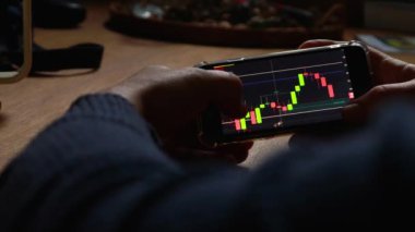 Adam evdeki cep telefonundan borsa grafiğini kontrol ediyor. iş ve finans konsepti yüksek kaliteli video. Siyah arkaplan ekranı. 