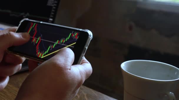 男人在家里用他的手机查看股票市场图表 商业和金融概念高质量的视频 黑色背景屏幕 — 图库视频影像