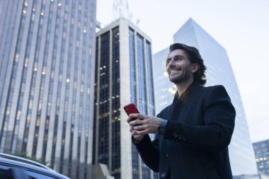 Alacakaranlıkta akıllı telefonlu genç adam manzarası ve arka planda şehir manzarası. Yüksek kalite fotoğraf. 
