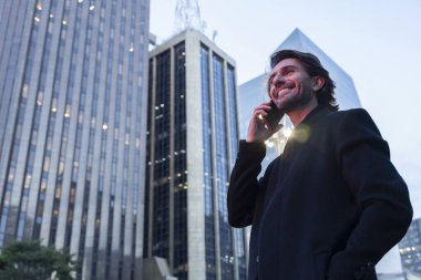 Alacakaranlıkta akıllı telefonlu genç adam manzarası ve arka planda şehir manzarası. Yüksek kalite fotoğraf. 