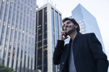 Alacakaranlıkta akıllı telefonlu genç adam manzarası ve arka planda şehir manzarası. Yüksek kalite fotoğraf. 