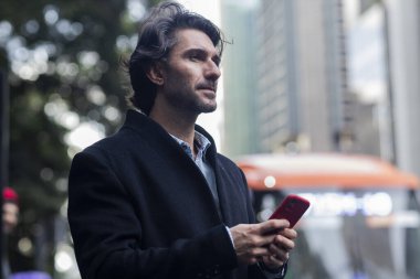 Gündüz vakti akıllı telefonlu genç adam manzarası ve arka planda şehir manzarası. Yüksek kalite fotoğraf. 