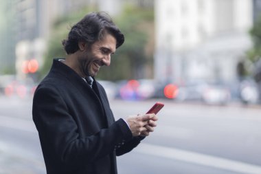 Gündüz vakti akıllı telefonlu genç adam manzarası ve arka planda şehir manzarası. Yüksek kalite fotoğraf. 