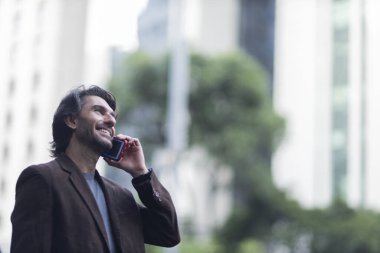Gündüz vakti akıllı telefonlu genç adam manzarası ve arka planda şehir manzarası. Yüksek kalite fotoğraf. 