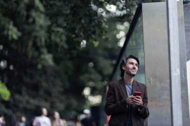 Gündüz vakti akıllı telefonlu genç adam manzarası ve arka planda şehir manzarası. Yüksek kalite fotoğraf. 