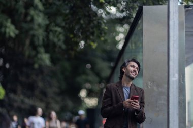 Gündüz vakti akıllı telefonlu genç adam manzarası ve arka planda şehir manzarası. Yüksek kalite fotoğraf. 