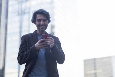 Gündüz vakti akıllı telefonlu genç adam manzarası ve arka planda şehir manzarası. Yüksek kalite fotoğraf. 