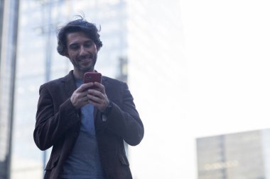 Gündüz vakti akıllı telefonlu genç adam manzarası ve arka planda şehir manzarası. Yüksek kalite fotoğraf. 