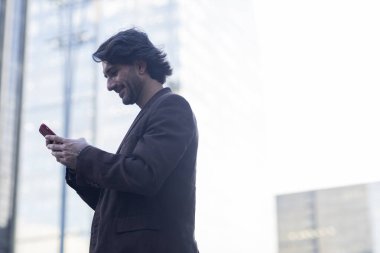 Gündüz vakti akıllı telefonlu genç adam manzarası ve arka planda şehir manzarası. Yüksek kalite fotoğraf. 