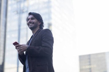 Gündüz vakti akıllı telefonlu genç adam manzarası ve arka planda şehir manzarası. Yüksek kalite fotoğraf. 