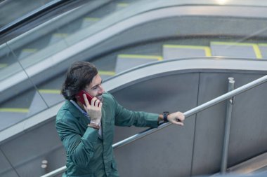 View of young man using a smartphone inside a subway - metro station with a blurred view landscape in the background. High quality photo. Talking on the phone.  clipart