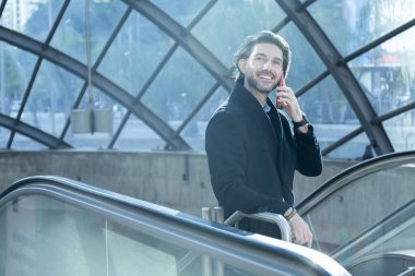 Arka planda bulanık bir manzara olan kapalı alanda akıllı telefon kullanan genç bir adamın görüntüsü. Yüksek kalite fotoğraf. Telefonda konuşuyorlar.. 